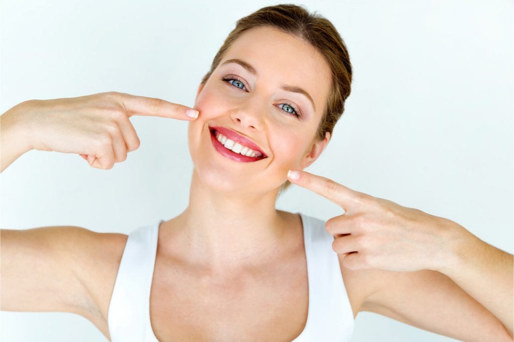 The pretty woman is showing off her beautiful and white teeth.